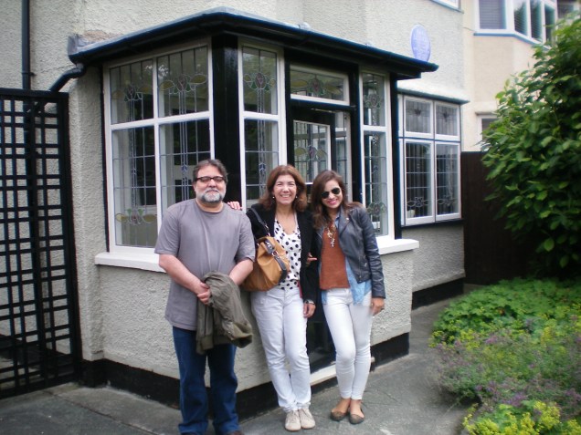 Felizes depois da visita, na frente da casa de John Lennon, com o selo azul ao fundo, indicando que morou alguém ilustre